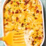 Baked cauliflower casserole topped with bacon and green onions
