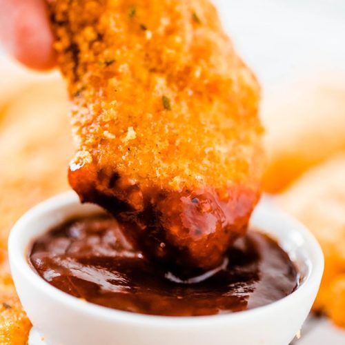 Easy Oven Baked Crispy Chicken Tenders dipped in barbeque sauce