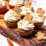 Keto gingerbread cupcakes topped with cinnamon cream cheese frosting on a white plate, garnished with a sprinkle of cinnamon.