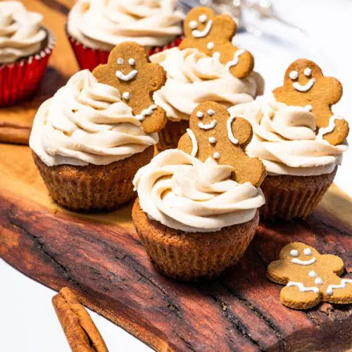 Keto Gingerbread Cupcakes 7 Keto gingerbread cupcakes topped with cinnamon cream cheese frosting on a white plate, garnished with a sprinkle of cinnamon.