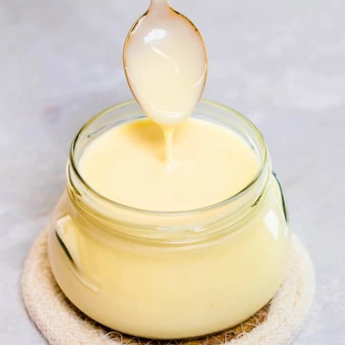 Keto Condensed Milk 9 Gold spoon scooping creamy sugar-free condensed milk from a jar