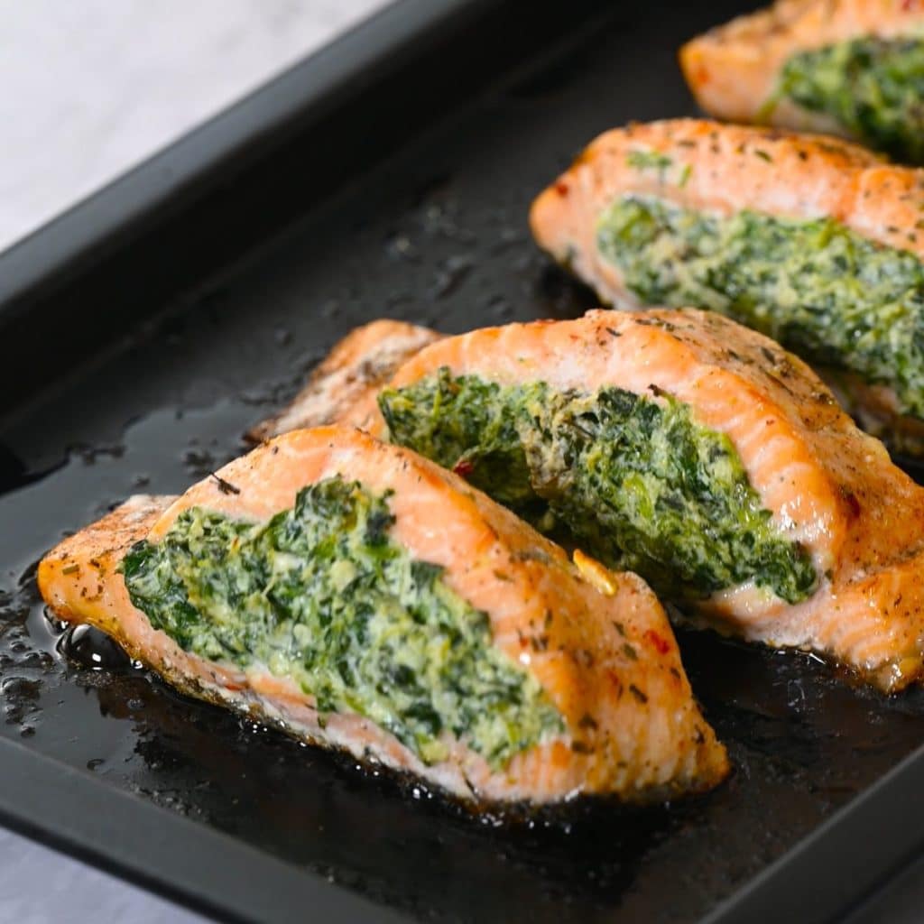 baked spinach stuffed salmon in a black baking tray