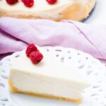 keto cheesecake slice on a plate with raspberry on top