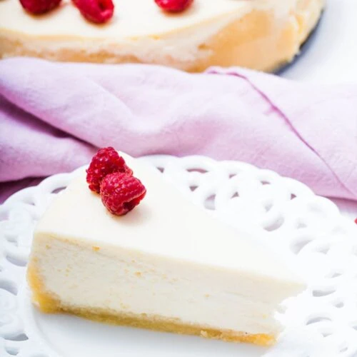 The Best Keto Cheesecake 18 keto cheesecake slice on a plate with raspberry on top