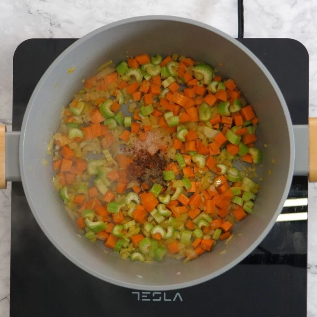 Roasted Red Pepper Soup 12 Onions, carrots, and celery sautéing in olive oil in a pot as the flavor base for roasted red pepper soup.