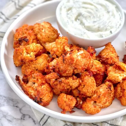 Air Fryer Buffalo Cauliflower 10 Air Fryer Buffalo Cauliflower bites served on a white plate and ranch dressing on the side