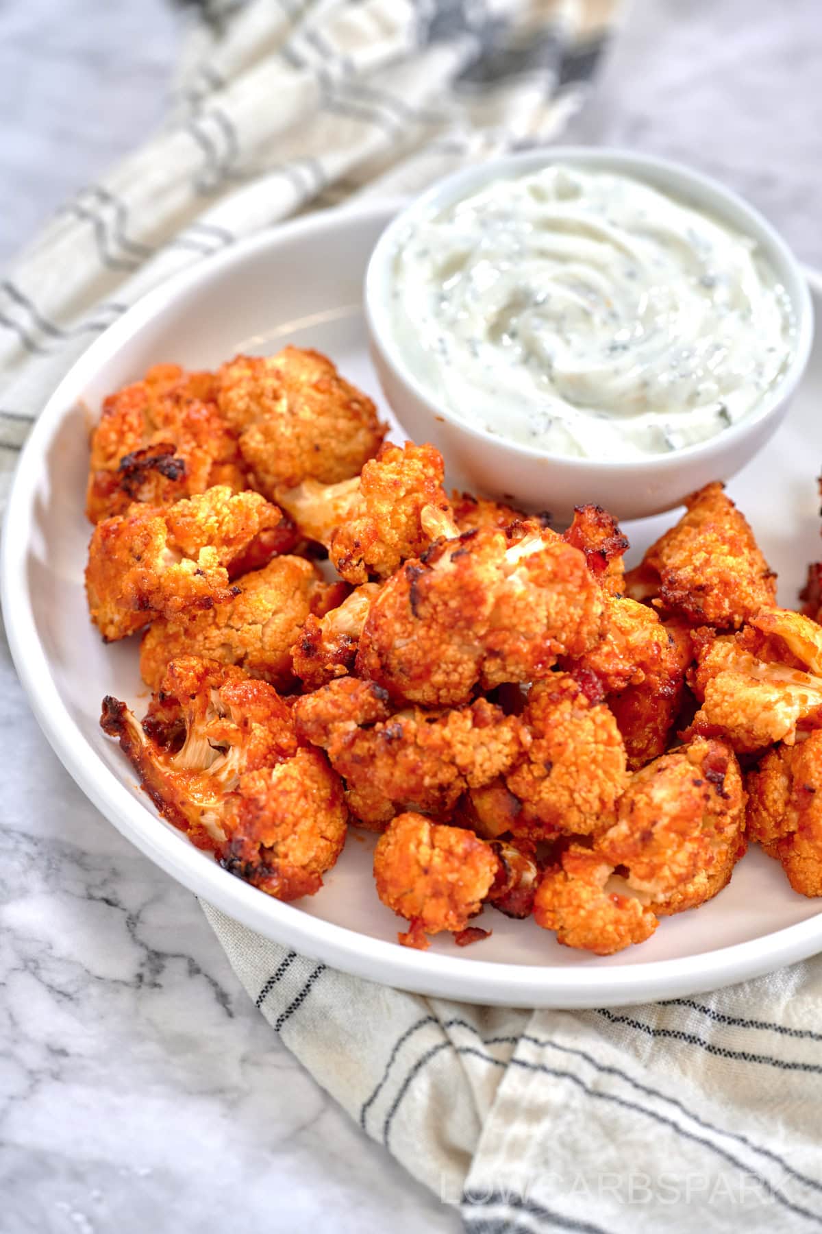 Air Fryer Buffalo Cauliflower bites served on a white plate and ranch dressing on the side