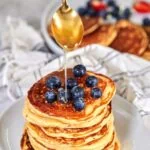 a stack of pancakes with blueberries and syrup