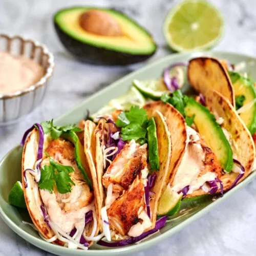 Fish Tacos 13 Juicy fish tacos topped with creamy sauce, crunchy cabbage, and fresh lime on a warm tortilla.