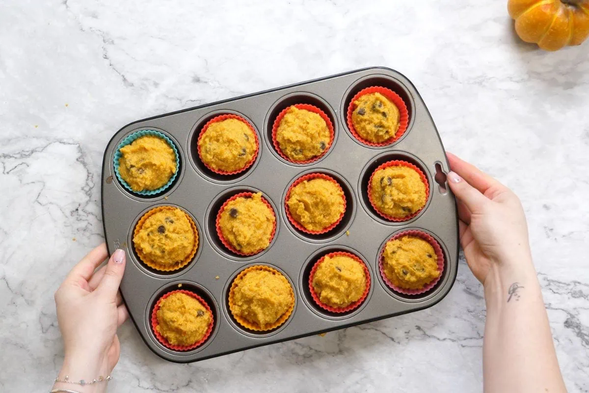 Chocolate Chip Pumpkin Muffins 7 Scooping keto pumpkin muffin batter into colorful silicone liners.