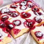 view of freshly baked berry cottage cheese clafoutis in a baking dish, golden-brown with juicy berries on top.