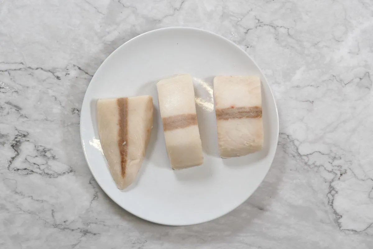 Fish Tacos 4 Unseasoned flaky white fish on plate, showing ideal portion sizes.