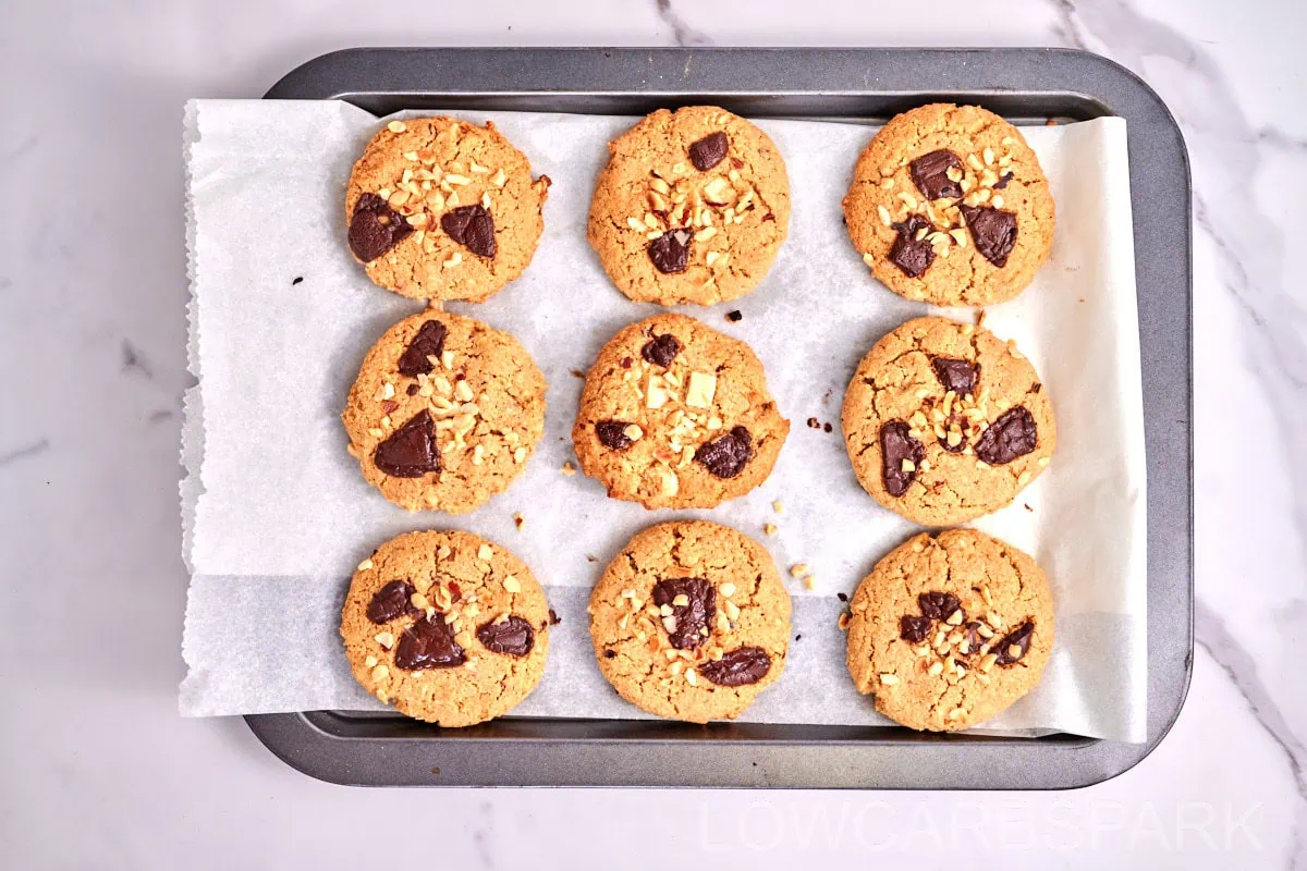 Keto Marry Me Cookies 4 Freshly baked low-carb cookies with chocolate chunks and nuts on a metal baking tray.