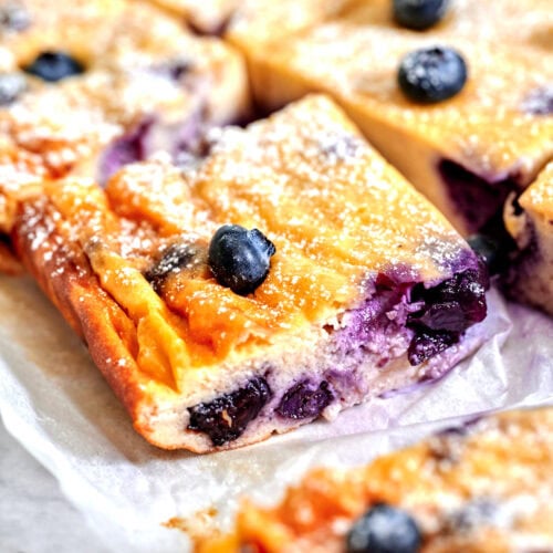 Healthy high-protein Greek yogurt bars topped with fresh blueberries, cooling on parchment.
