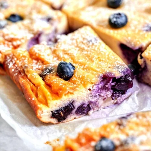 Greek Yogurt Bake 11 Healthy high-protein Greek yogurt bars topped with fresh blueberries, cooling on parchment.