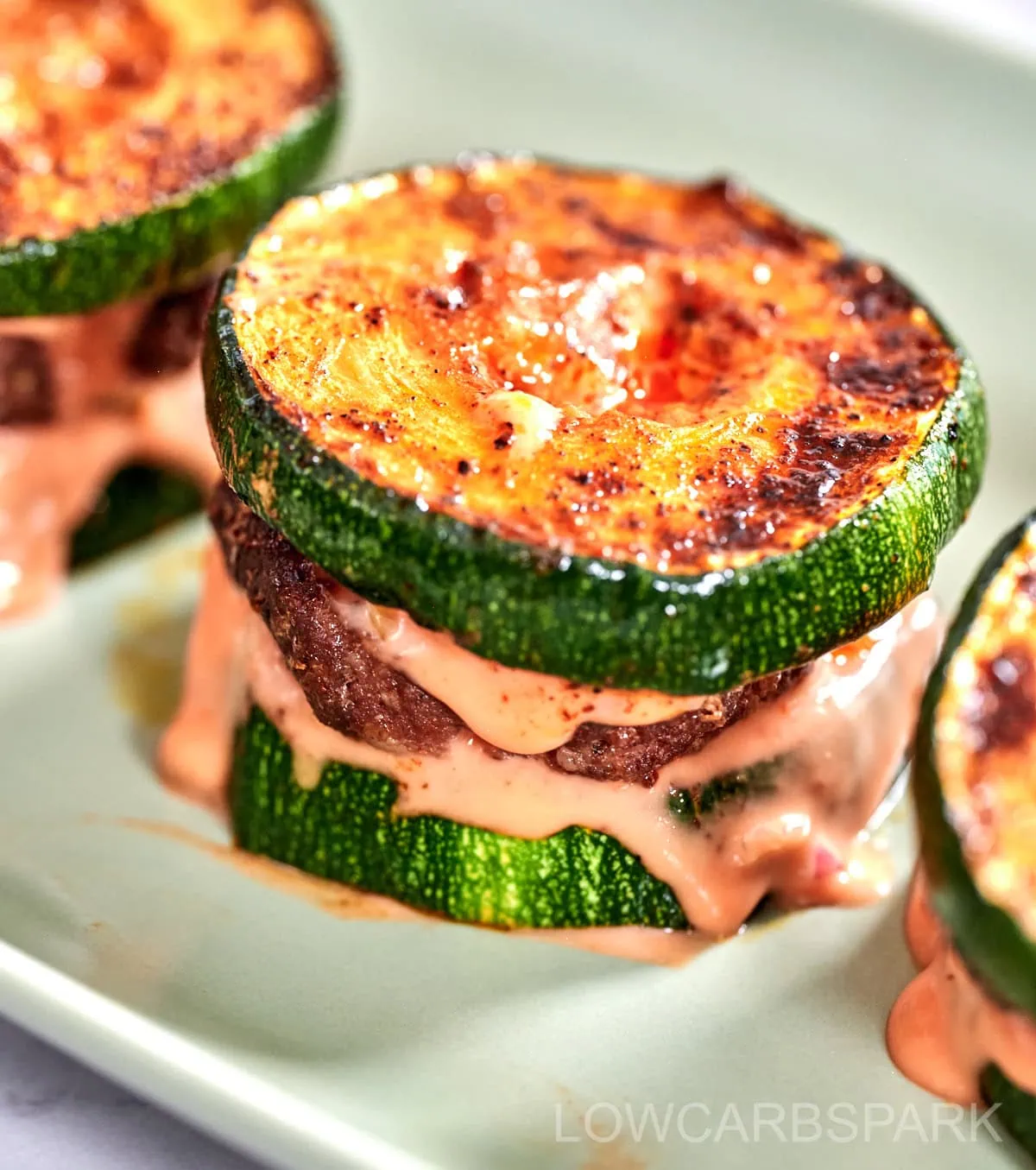 Zucchini Sliders 2 Close-up of zucchini slider with grilled marks and sauce oozing out.