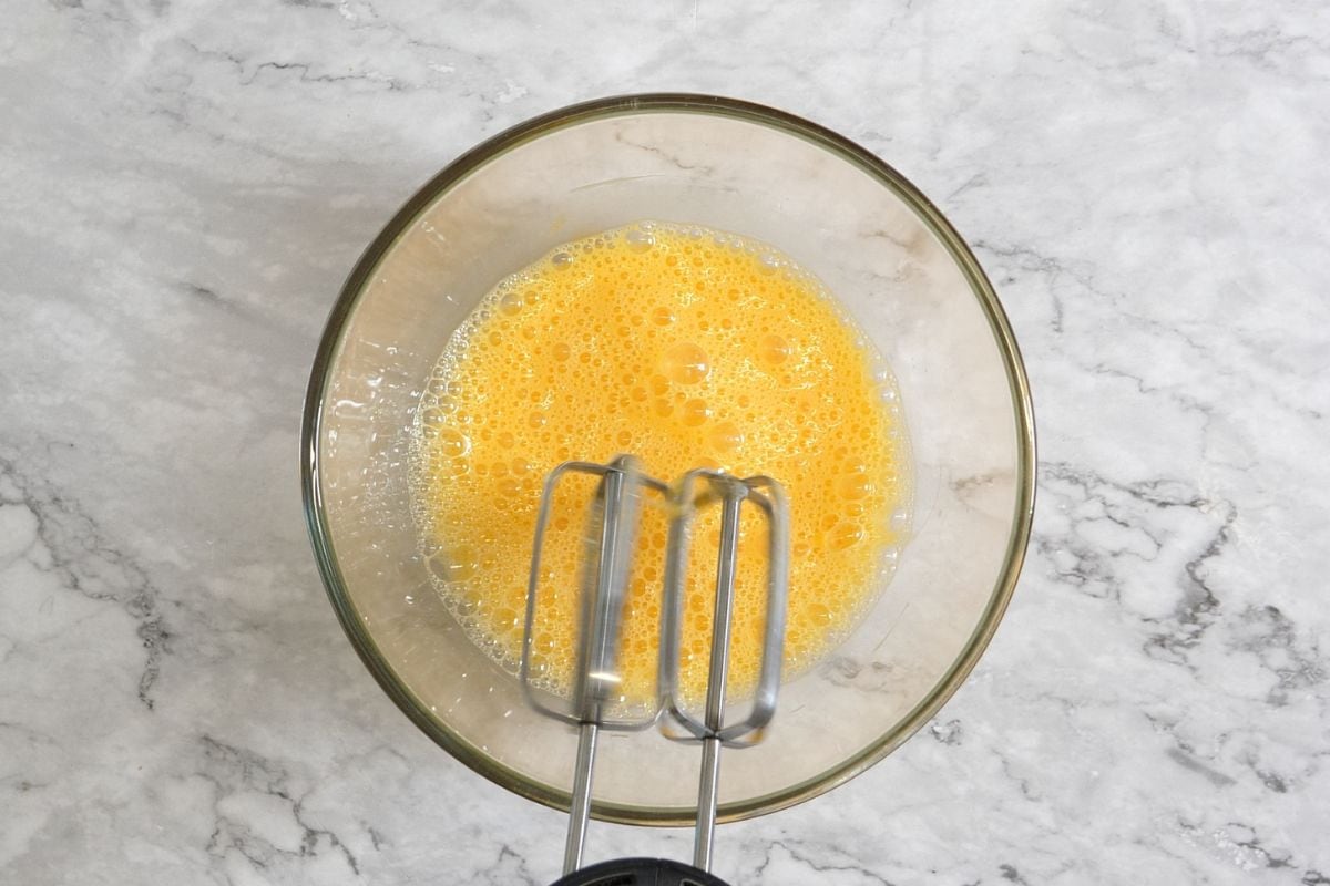 Preparing the egg base for Greek yogurt bake in a glass bowl.