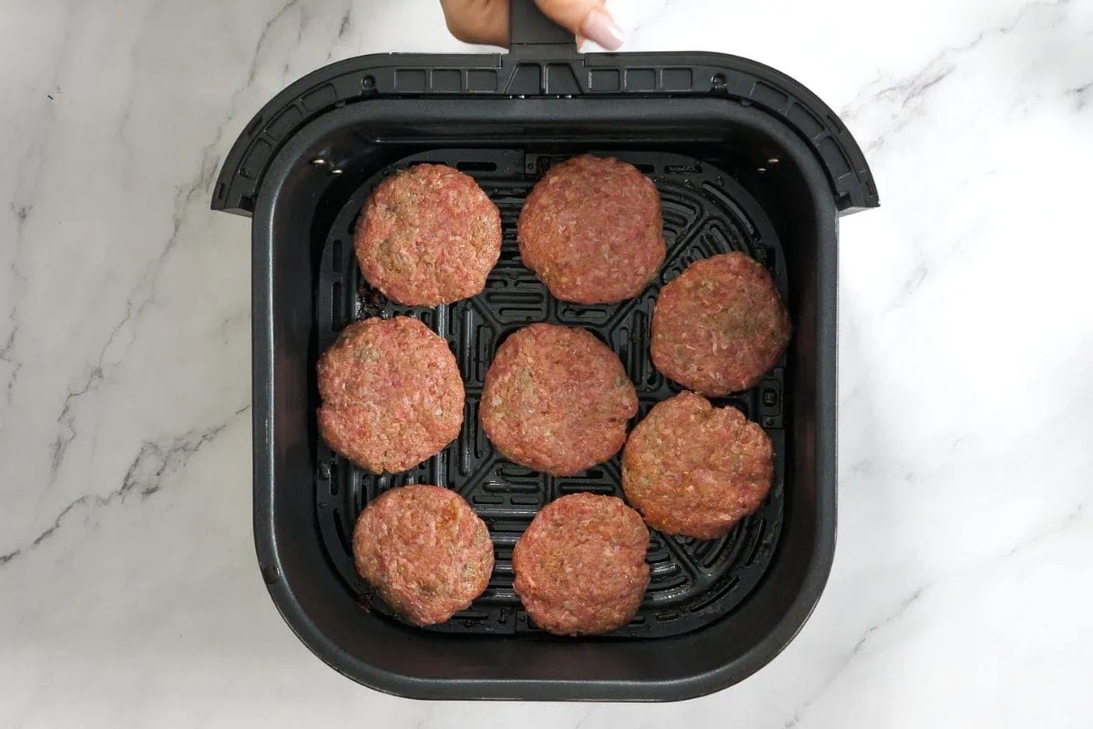 Zucchini Sliders 6 Raw beef patties neatly arranged in an air fryer basket.