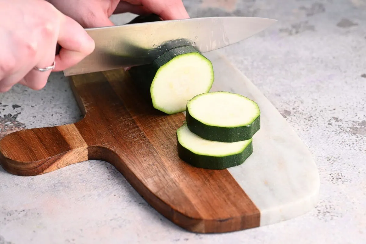 Zucchini Sliders 3 Cutting fresh zucchini into thick round slices on a cutting board.