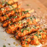 Air fryer ranch garlic parmesan chicken skewers topped with fresh herbs and melted butter.