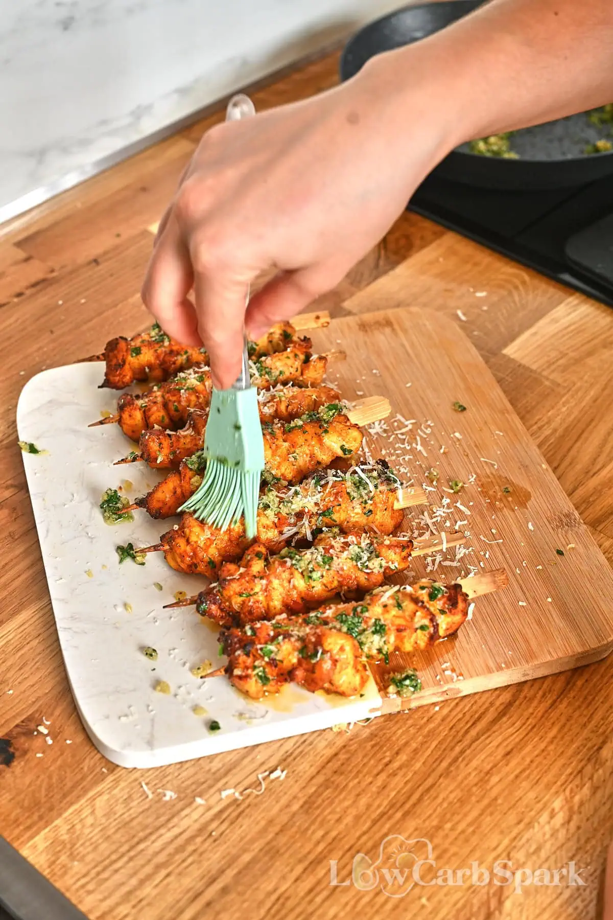 Ranch Garlic Parmesan Chicken Skewers 10 Hand brushing garlic butter over freshly cooked air fryer ranch chicken skewers.