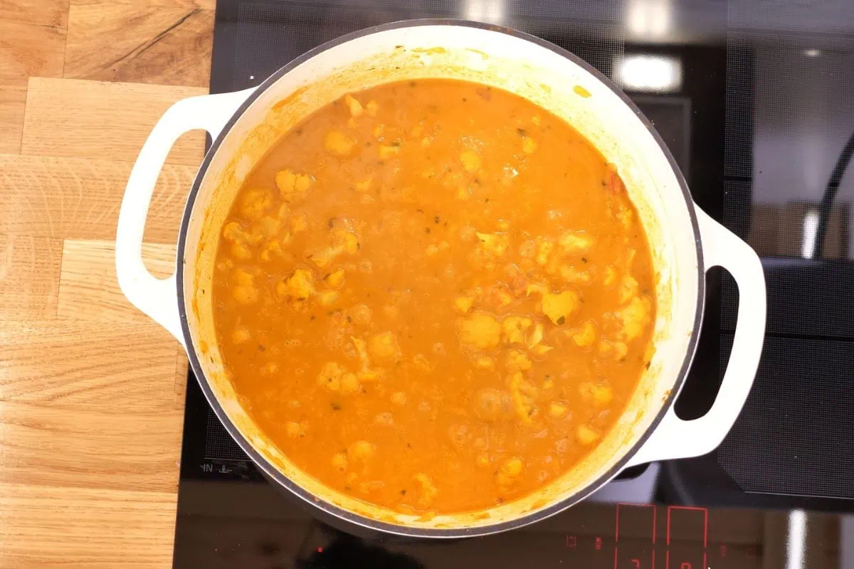 Cauliflower Curry 8 auliflower curry simmering in a Dutch oven on stovetop.