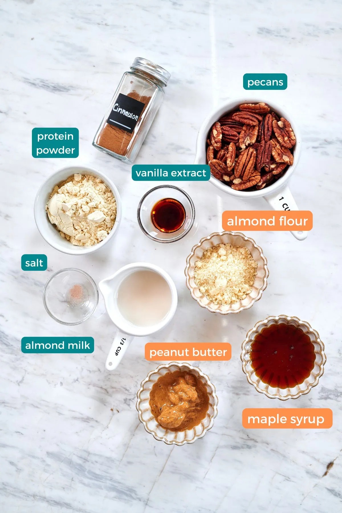 High-Protein Pecan Pie Balls 3 Overhead view of ingredients for high-protein keto pecan pie balls, including pecans, almond flour, peanut butter, protein powder, and maple syrup.