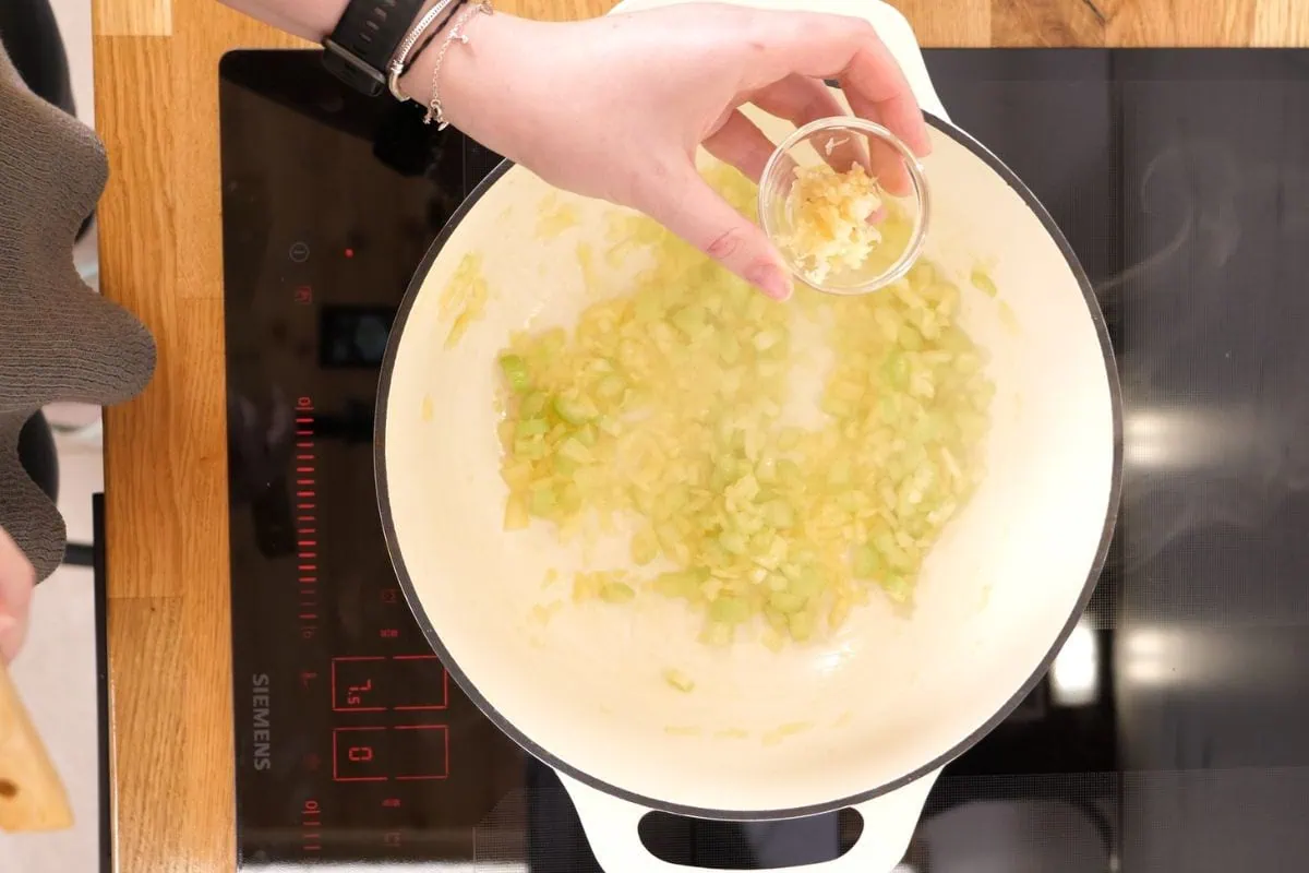Creamy Turkey Soup 5 sautéing minced garlic and celery in a white Dutch oven on the stovetop.