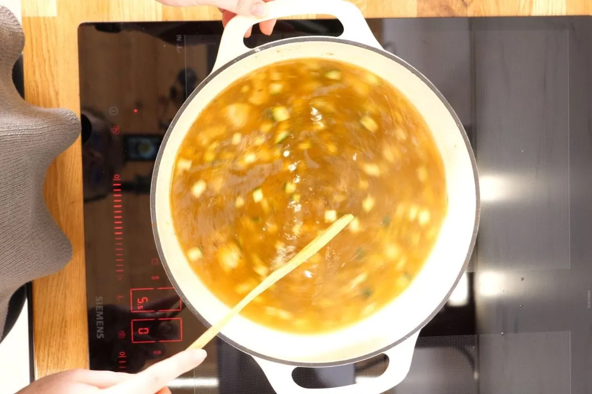 Creamy Turkey Soup 7 Stirring pot of simmering turkey soup with broth and vegetables.