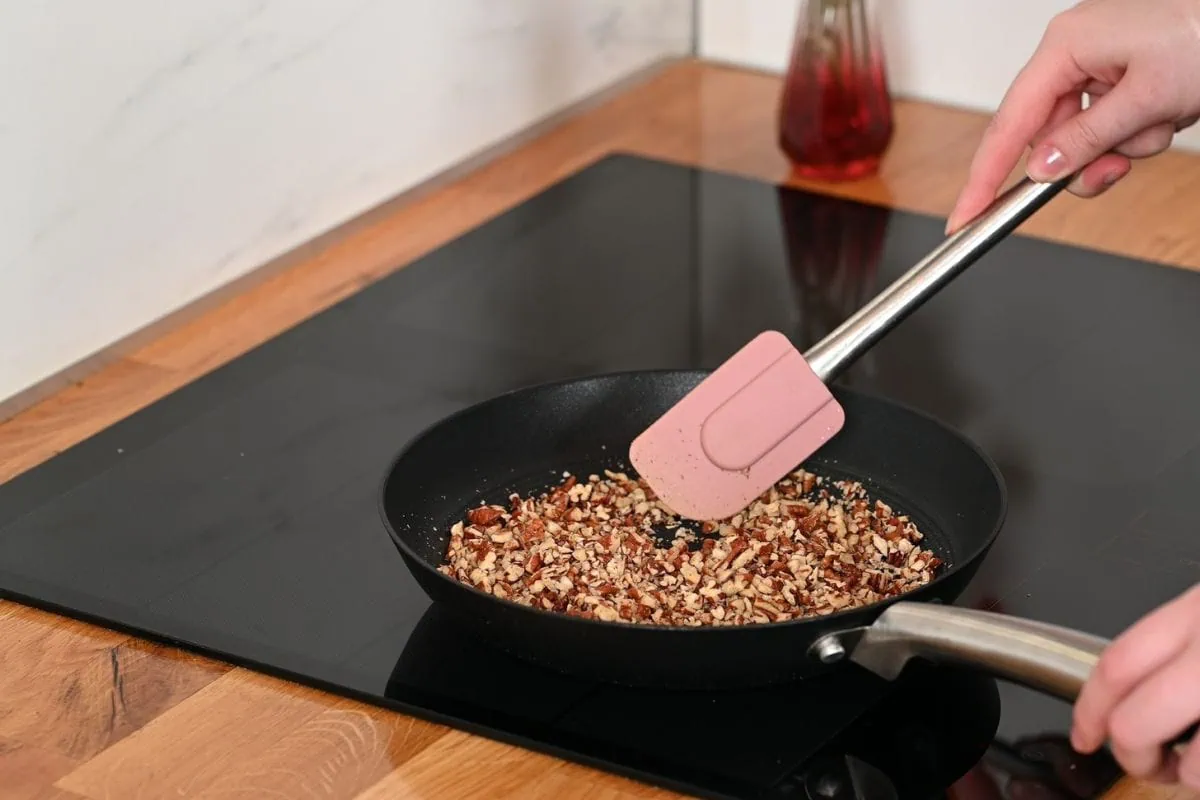 High-Protein Pecan Pie Balls 4 Toasting chopped pecans in a non-stick pan for keto pecan pie protein balls.