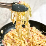 Low-carb cabbage carbonara in a skillet with creamy cheese sauce and crispy pancetta.