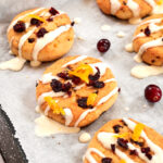 Freshly baked cranberry orange cookies drizzled with icing and topped with dried cranberries and orange zest.