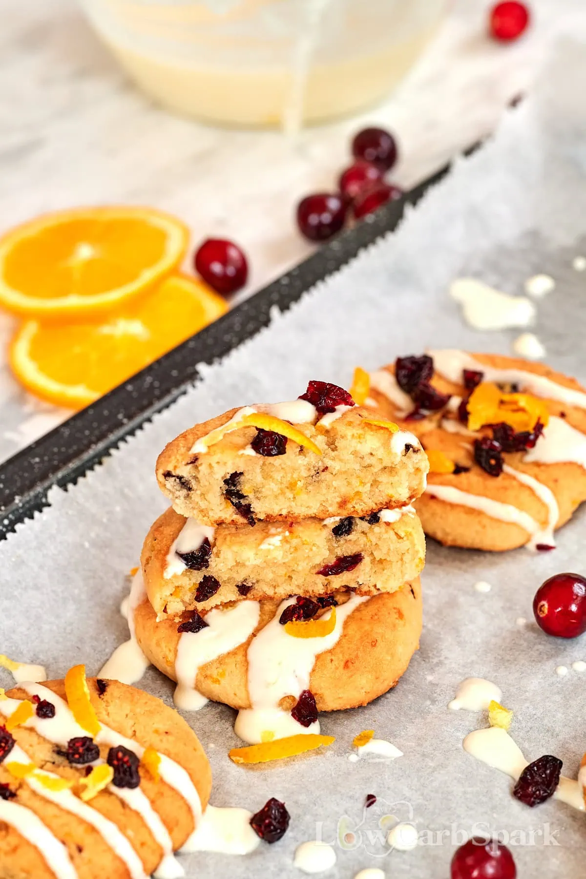 Almond Flour Cranberry Orange Cookies 11 Stacked cranberry orange cookies with a soft, tender center, drizzled with icing and surrounded by cranberries and orange slices.