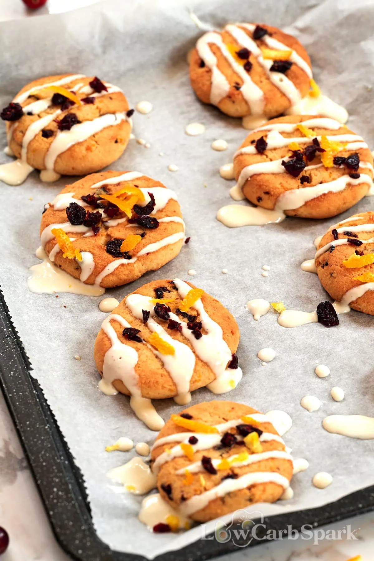 Almond Flour Cranberry Orange Cookies 2 Baking tray lined with cranberry orange cookies drizzled with icing and topped with dried cranberries.