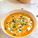 Creamy butternut squash soup topped with pumpkin seeds, parsley, and a swirl of coconut milk