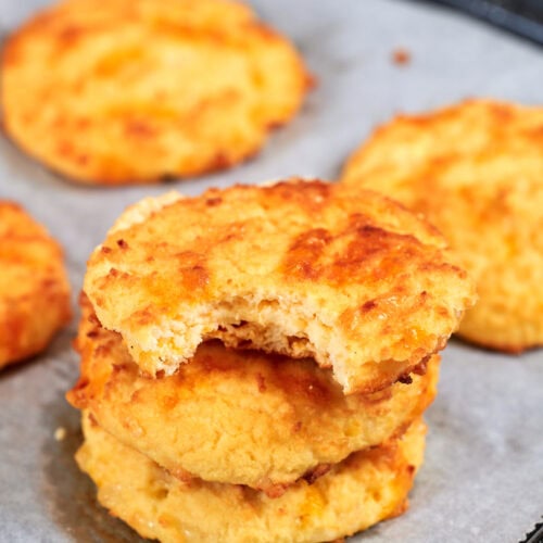 Low Carb Cottage Cheese Biscuits 10 Stack of fluffy cottage cheese biscuits made with coconut flour, with a bite taken to show the soft interior.