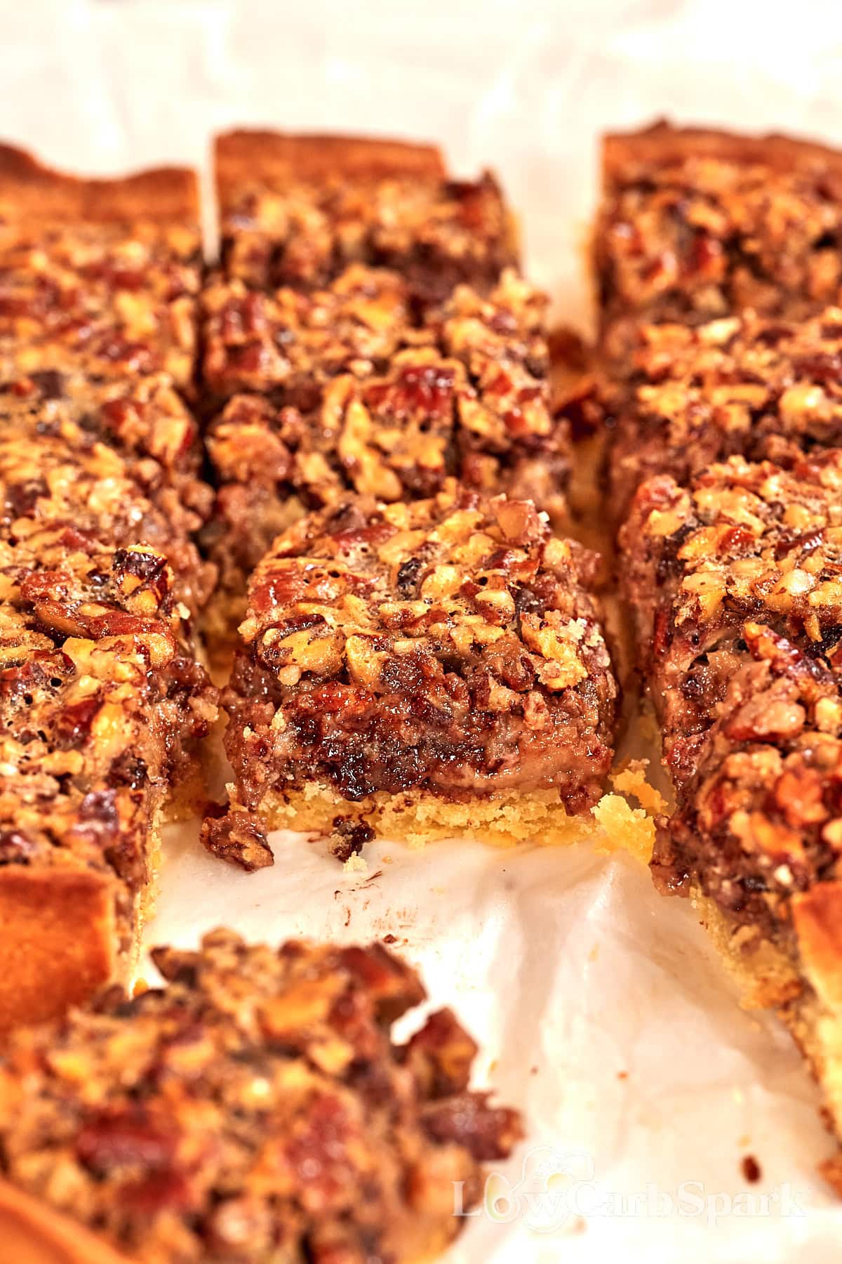 Freshly baked keto pecan pie bars cut into squares, showing a gooey pecan filling and golden crust.
