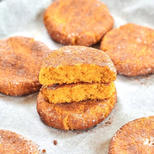 Keto Pumpkin Snickerdoodle Cookies 12 Stack of pumpkin snickerdoodle cookies coated in cinnamon with one cookie cut open