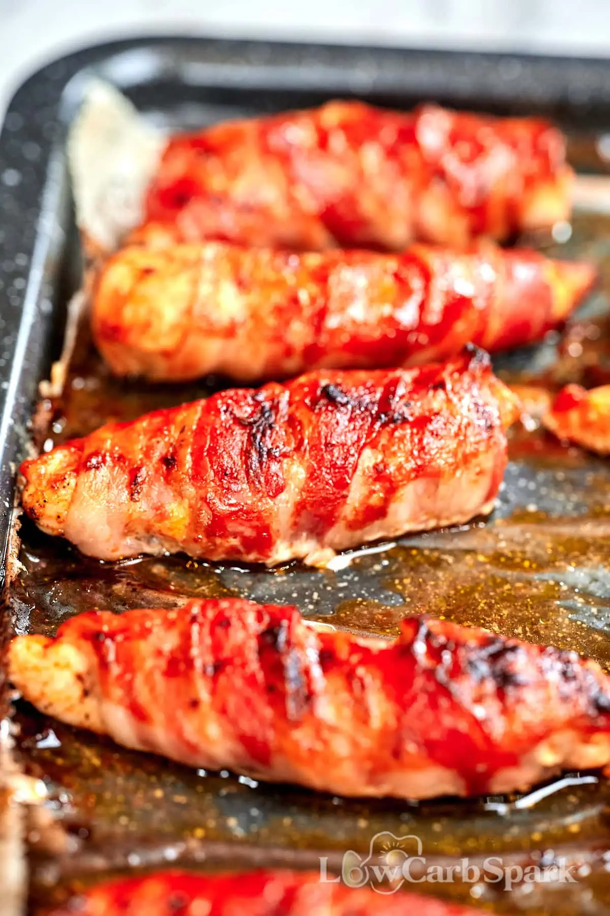 Barbecue Bacon-Wrapped Chicken Tenders 9 Barbecue bacon-wrapped chicken tenders baking on a sheet pan