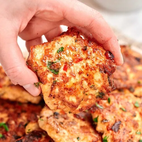 Cheesy Chicken Fritters 10 Cheesy chicken fritter held by hand, golden and crispy