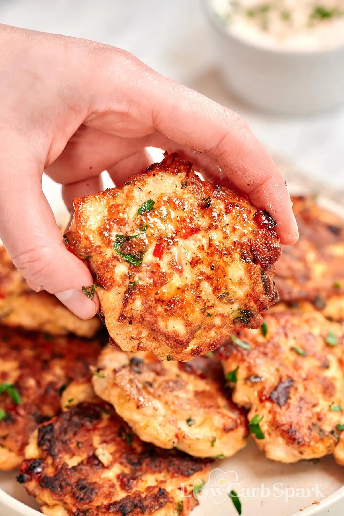 Cheesy Chicken Fritters 1 Cheesy chicken fritter held by hand, golden and crispy