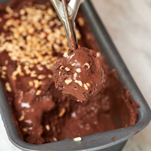 Chocolate Coconut Milk Ice Cream 8 Close-up of a scoop of chocolate coconut milk ice cream with chopped nuts being lifted from the pan.