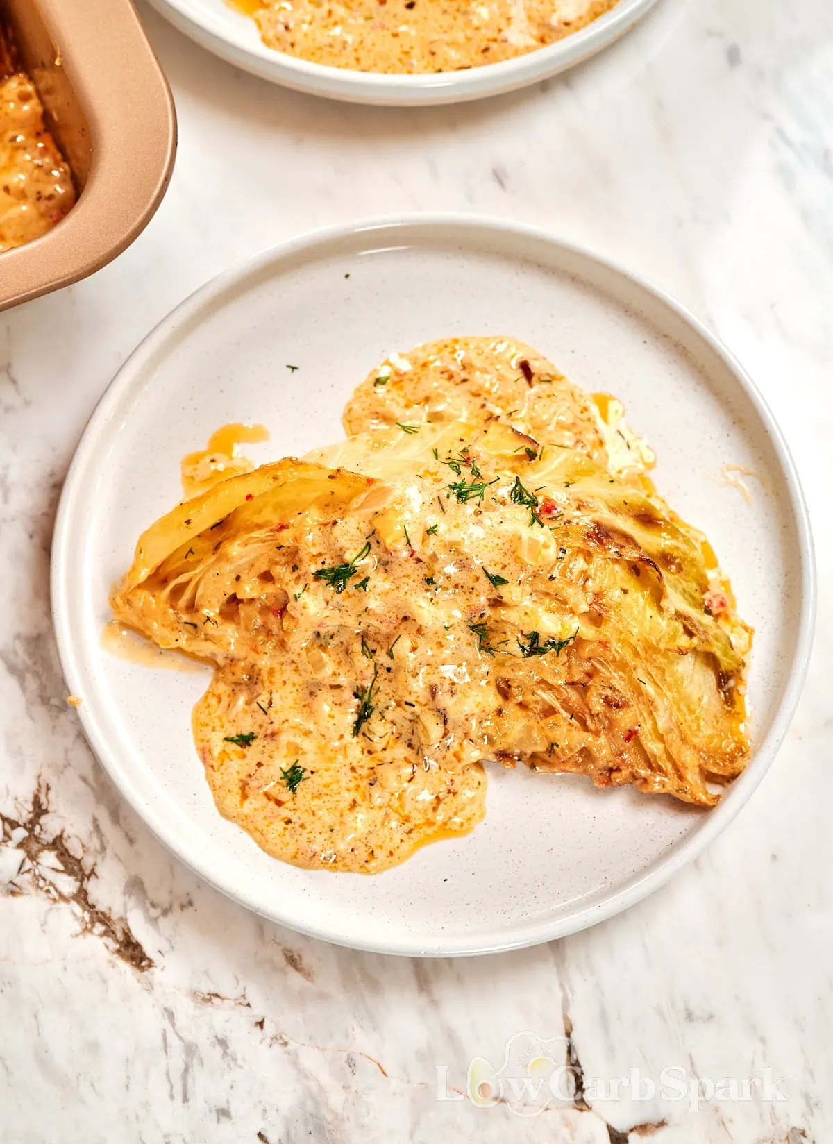 Creamy Garlic Butter Melting Cabbage 9 Single creamy baked cabbage wedge on a plate with rich parmesan garlic sauce.