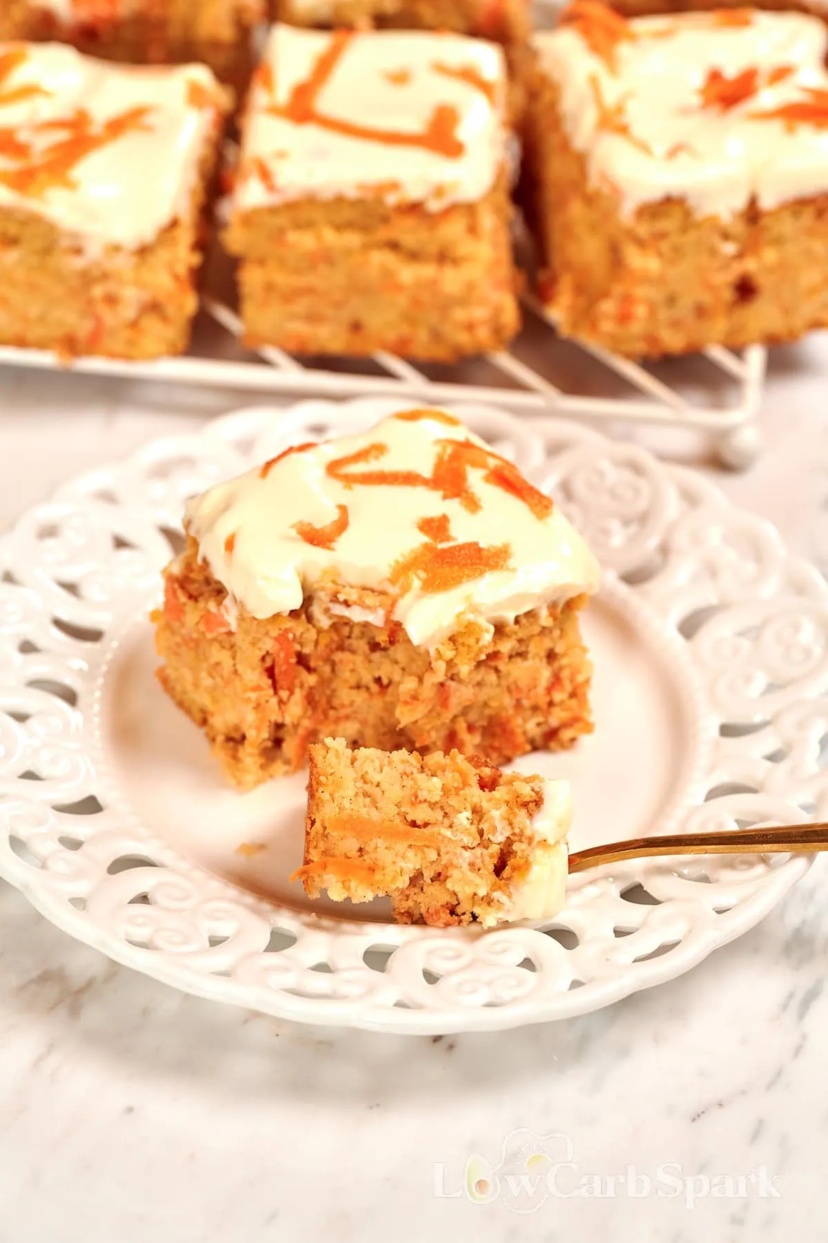 Cottage Cheese Carrot Cake Bars 1 High-protein cottage cheese carrot bars topped with creamy frosting and shredded carrots on a white plate.