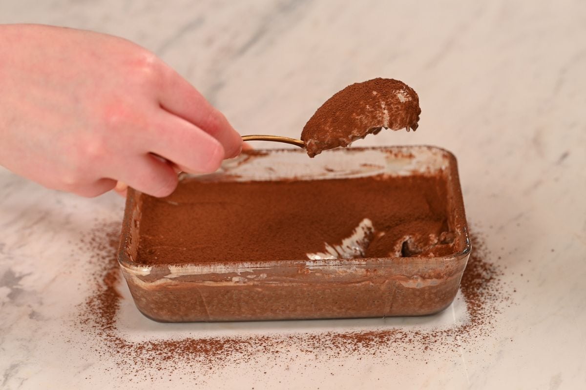 High Protein Tiramisu Chia Pudding 7 Spoon lifting a creamy bite of high protein tiramisu chia pudding topped with cocoa powder.