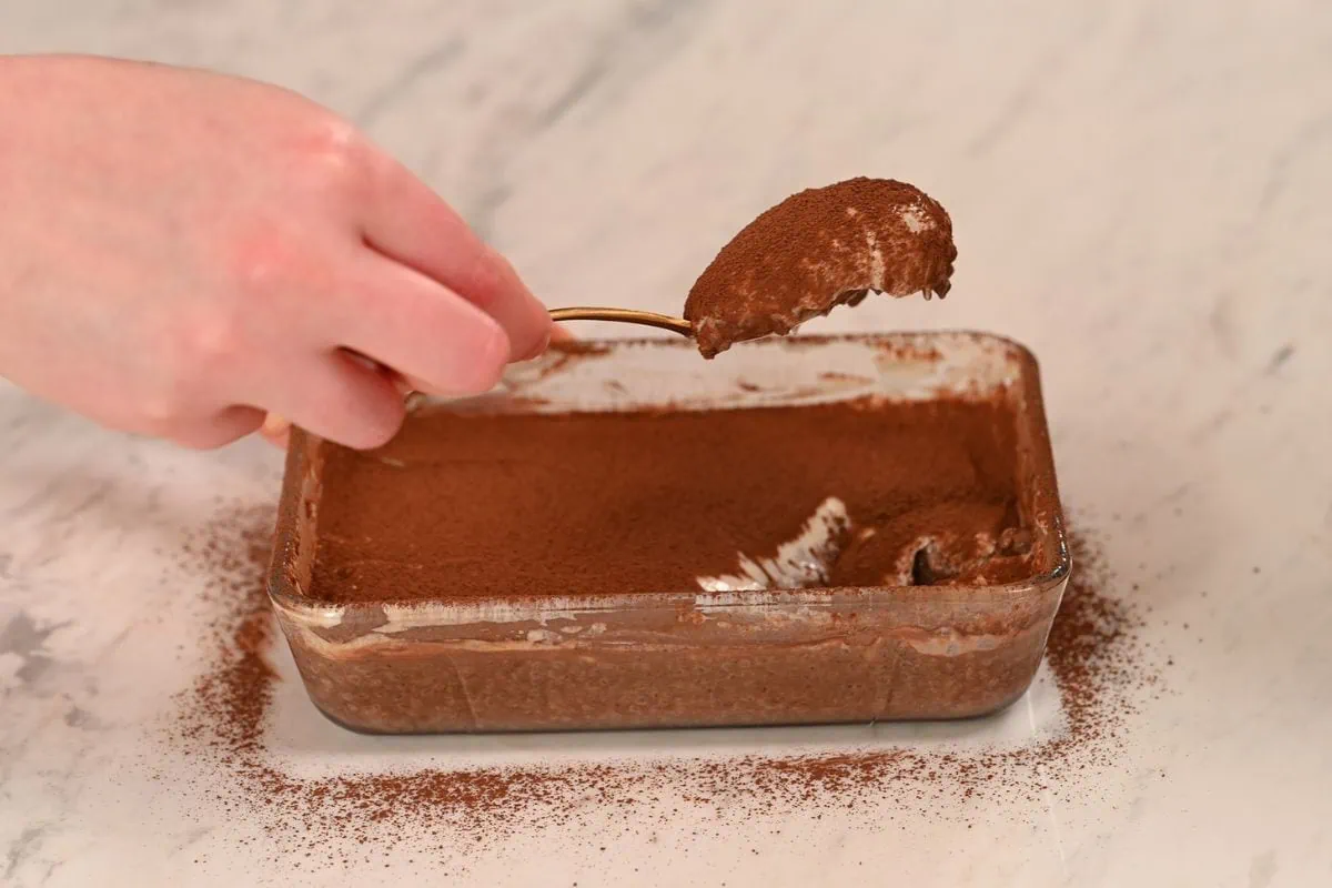 High Protein Tiramisu Chia Pudding 7 Spoon lifting a creamy bite of high protein tiramisu chia pudding topped with cocoa powder.