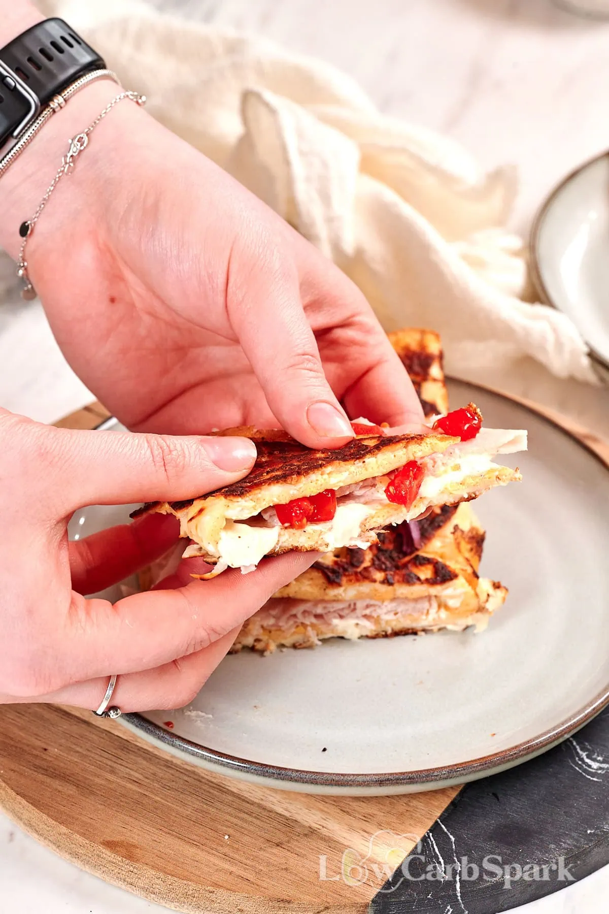 Crispy Halloumi Egg Wrap (High Protein, Low Carb) 2 Hands holding a crispy halloumi egg wrap with melted cheese, turkey, and fresh vegetables inside