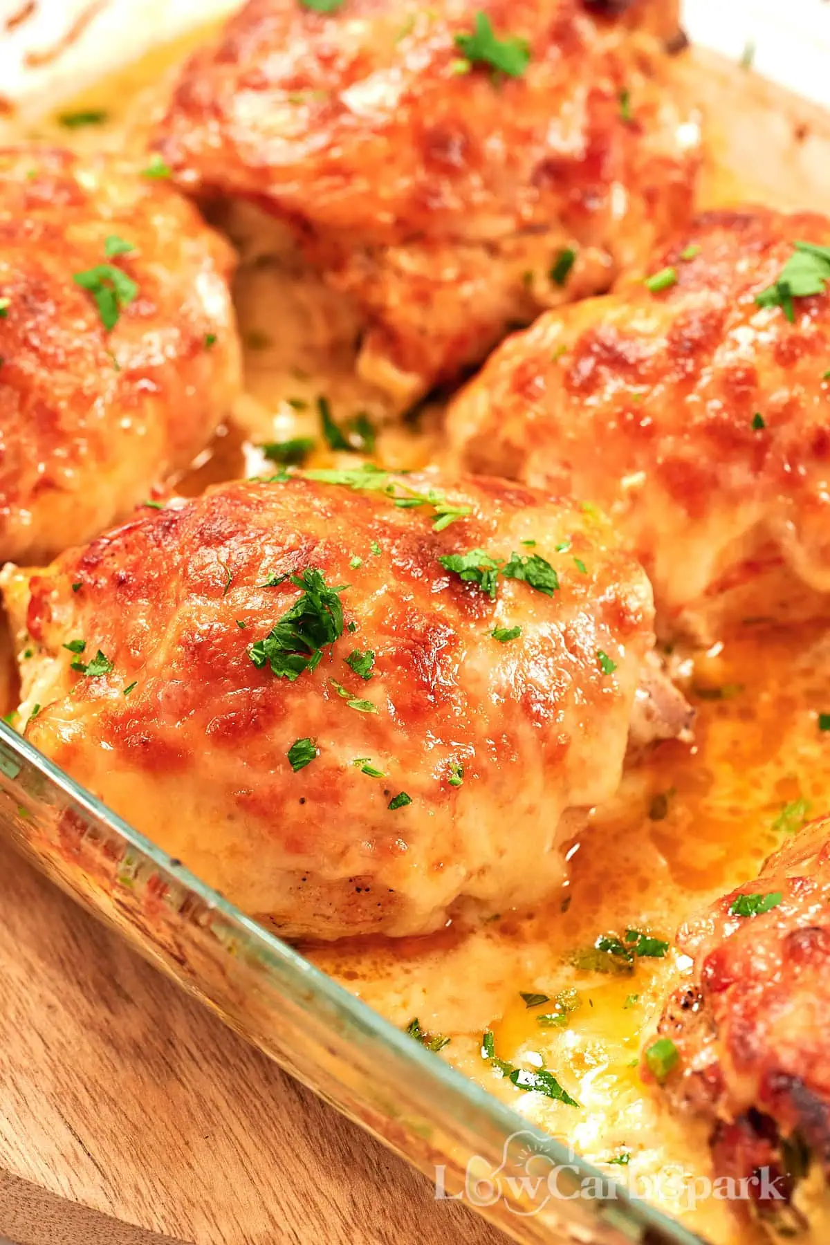Famous Chicken Breast Rolls 13 Close-up of baked chicken breast rolls topped with melted cheese and fresh herbs in a casserole dish