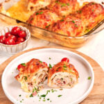 Sliced chicken breast roll with creamy filling served on a plate with melted cheese and herbs