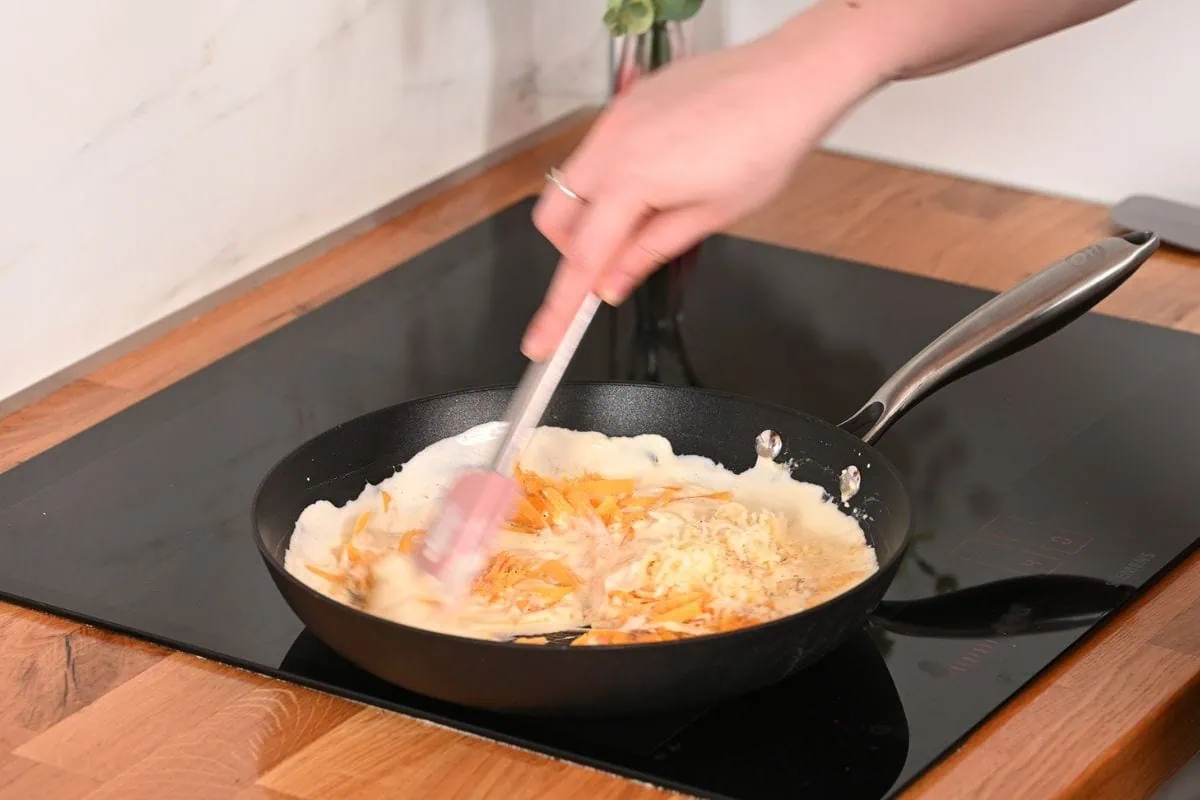 Creamy Cabbage Mac and Cheese 6 Stirring shredded cheese into creamy sauce in a skillet for cabbage mac and cheese
